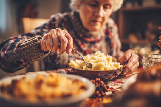 Elderly woman eating potato puree while sitting at dining table - Concept of Canadian Thanksgiving  