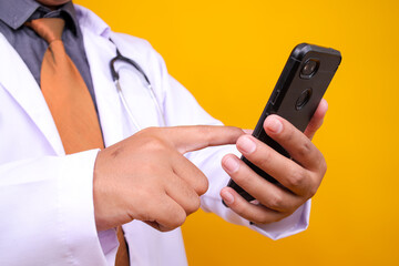Close-up Of A Medical Professional's Hands Interact With Mobile Phone Isolated On Yellow Background