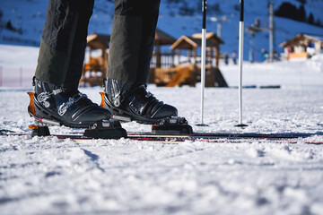 Ski boots on snow with poles in mountain resort