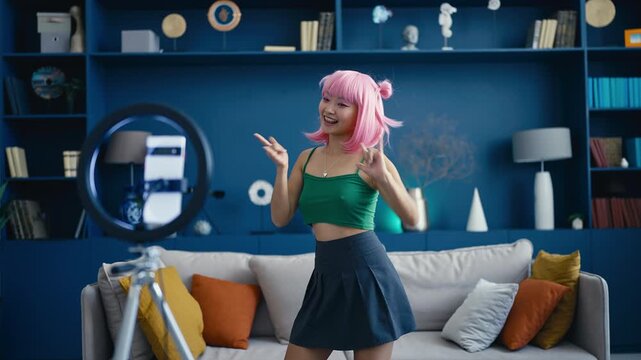 Cute Korean pink-haired woman recording k-pop dance video on phone, fun hobby