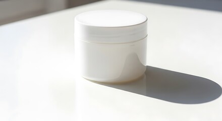 Empty white cosmetic jar on a white surface.