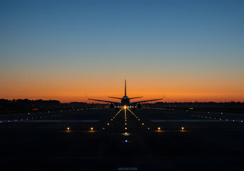 Fototapeta premium Airplane Landing at Sunset Aircraft Silhouette on Runway, Night Flight, Orange Sky, Dusk, Travel, Aviation.