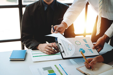 Young colleagues discuss business and analytical price charts using calculators and laptops to calculate financial, tax, accounting, statistics and analytical research ideas.