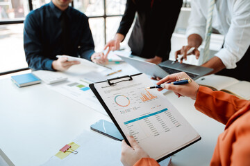 Young colleagues discuss business and analytical price charts using calculators and laptops to calculate financial, tax, accounting, statistics and analytical research ideas.