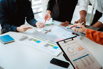 Young colleagues discuss business and analytical price charts using calculators and laptops to calculate financial, tax, accounting, statistics and analytical research ideas.