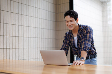 Young man smiling and working on his laptop in a modern office