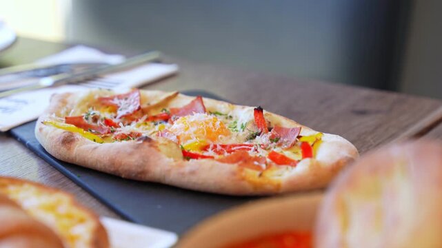 Close-up of a colorful Turkish pide topped with egg and vegetables&mdash;ideal for food, culinary culture, or restaurant-themed content with a focus on freshness and detail.