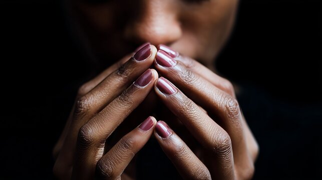Artistic close-up of fingers with elegant nail polish, conveying emotion and focus against a dark background.