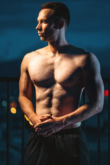 Muscular athlete posing powerfully at night, strength and dedication, Toned man with perfect body displaying power and discipline in evening silhouette