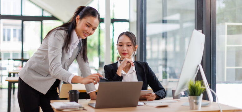 Business asian women Reviewing Documents, Two business meticulously reviewing a stack of documents, highlighting the details and precision in work.	
