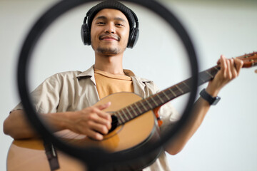 Young Asian Man Enjoying Playing Music Looking Towards The Camera With Headphones