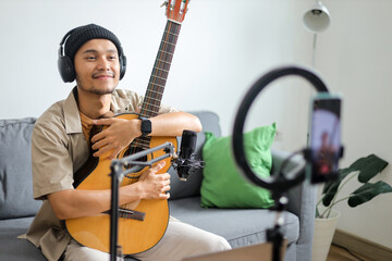 Smiling Young Asian Musician With Acoustic Guitar, Ready For Online Performance Or Recording