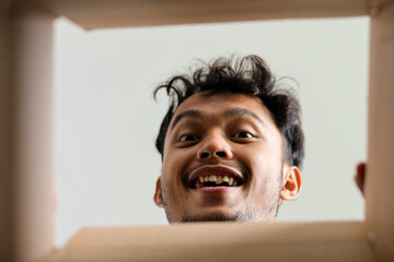 Excited Young Man Looking Down Into Package Smiling Happily From Unboxing Perspective