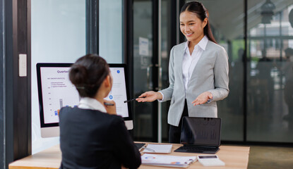 Asian business documents on office table with laptop computer and graph financial with social network diagram and three colleagues discussing data in the background
