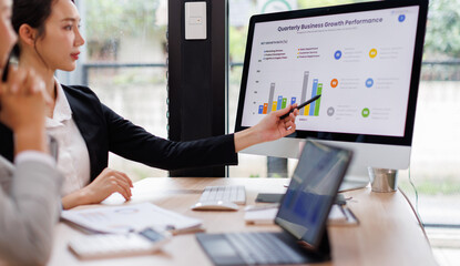 Asian business documents on office table with laptop computer and graph financial with social network diagram and three colleagues discussing data in the background
