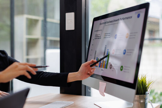 Asian business documents on office table with laptop computer and graph financial with social network diagram and three colleagues discussing data in the background
