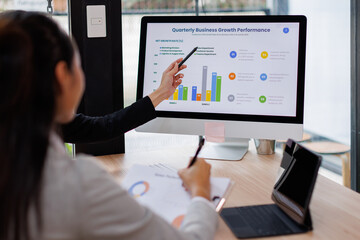 Asian business documents on office table with laptop computer and graph financial with social network diagram and three colleagues discussing data in the background
