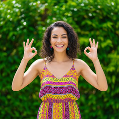 happy young woman showing thumbs up. Cheerful young woman in a colorful outfit gesturing OK with both hands isolated on vibrant green background.