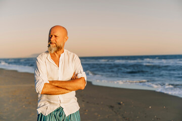 Elderly man gazing at sea during golden hour on the beach