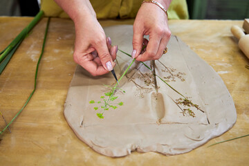 Removing flowers and leaves from clay to reveal detailed botanical imprints for plaster relief....