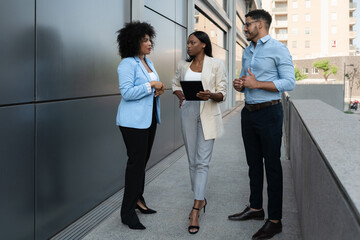 Multiracial diverse business team having a conversation outside the office using a digital tablet