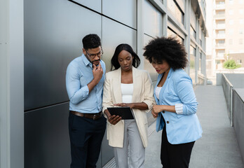 Diverse Multiracial business team analyzing data on digital tablet outside office building