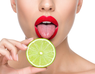 A close-up of a woman with red lipstick sticking out her tongue near a fresh lime slice held by her hand against a black background.