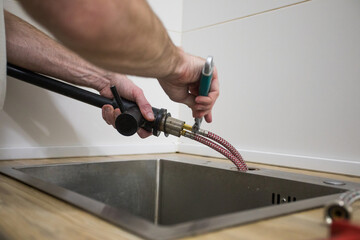 Professional plumber fixing water tap in kitchen, closeup