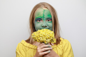 Cheerful young girl child with green face paint makeup. Halloween ogre look
