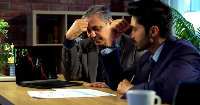 Indian investors worried on market crash, Asian young corporate executives or financial experts looking tense while analyzing stock charts, discussing investment losses and economic downturn