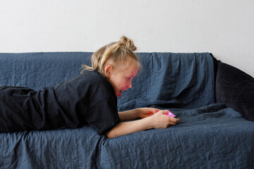 Happy girl using mobile phone on sofa at home