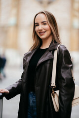 Smiling woman crossing street with suitcase