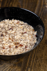 porridge with dried fruits in a black bowl , cooking instant oatmeal porridge, chia in porridge, top view