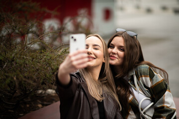 Two happy friends taking selfie together outdoors