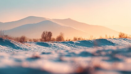 Serene winter landscape at sunrise, snow-covered foreground with distant mountain range bathed in warm light