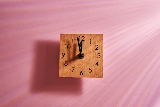 square wood material alarm clock against pink background