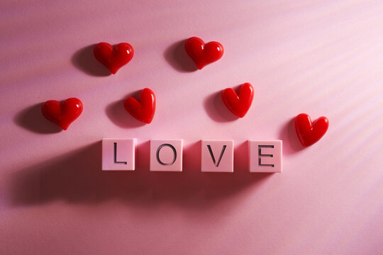  red heart shape beside toy blocks with text LOVE  against pink background