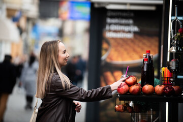 Smiling woman buying pomegranate juice from street vendor