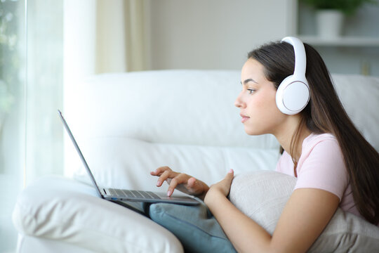 Serious woman wearing headphone browsing on laptop