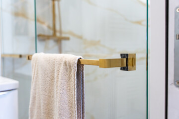 Zoom sur les différents éléments d’une salle de bain moderne avec marbre blanc à rainures dorées, colonne de douche, robinetterie et accessoires en finition bronze doré.