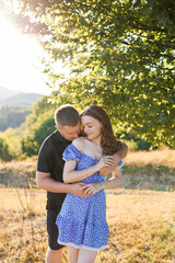 Fototapeta premium Couple enjoying a warm sunset embrace in a sunny outdoor field