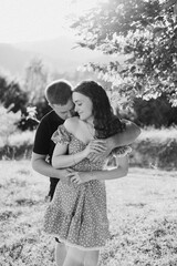 Young couple embraces in a sunlit meadow during a warm summer afternoon