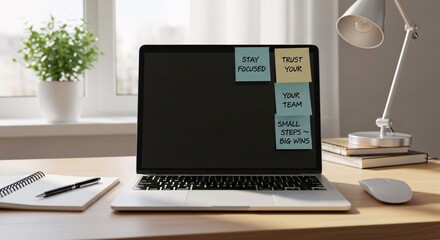 Laptop with motivational sticky notes on a wooden desk next to a window with a potted plant and a desk lamp