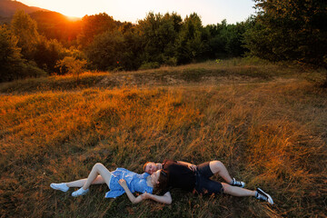 Couple relaxes on grassy field during sunset in serene mountain landscape