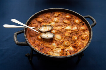 A large skillet of shakshouka, a popular Maghrebi dish in the Middle East and Israel comprised of eggs poached in a sauce of tomatoes, olive oil, peppers, onion and garlic.