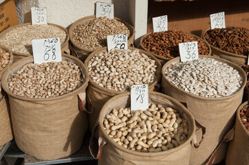 Assorted nuts and seeds, including peanuts, pistachios, almonds and watermelon seeds in large cloth baskets at an open air market in Tel Aviv, Israel.