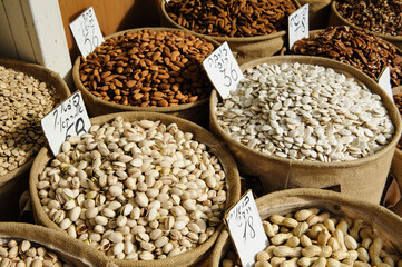 Assorted nuts and seeds including pistachios, almonds and peanuts in large burlap baskets at an open air market in Tel Aviv, Israel.