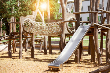 Playground Equipment. Modern Wooden Playground with Slide and Climbing Frame from Robinia Wood with Sunlight in Summer. 