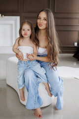 Happy mother and daughter share playful moment in matching outfits indoors