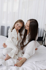 Mother and daughter enjoy playful moment together on bed in cozy room during morning